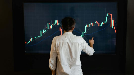Person analyzing a large financial chart on a screen, symbolizing secure data collaboration and multi-party computation for financial analytics.