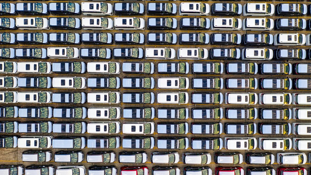 Aerial view of rows of parked new cars, representing automotive production, fleet management, and vehicle data collection.
