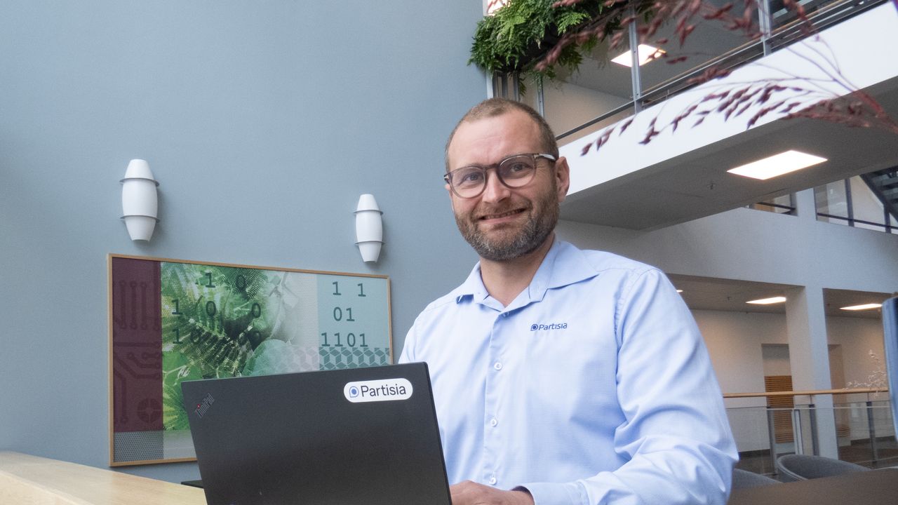 Partisia COO, Peter F. Frandsen, smiling while working on a laptop with a Partisia sticker.