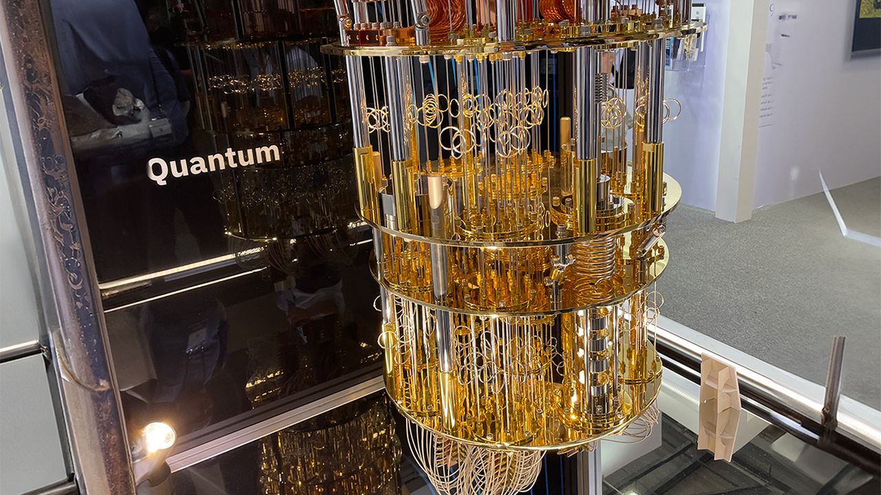 Quantum computer processor unit on display, showing intricate gold and metal wiring in a cylindrical, multi-layered structure