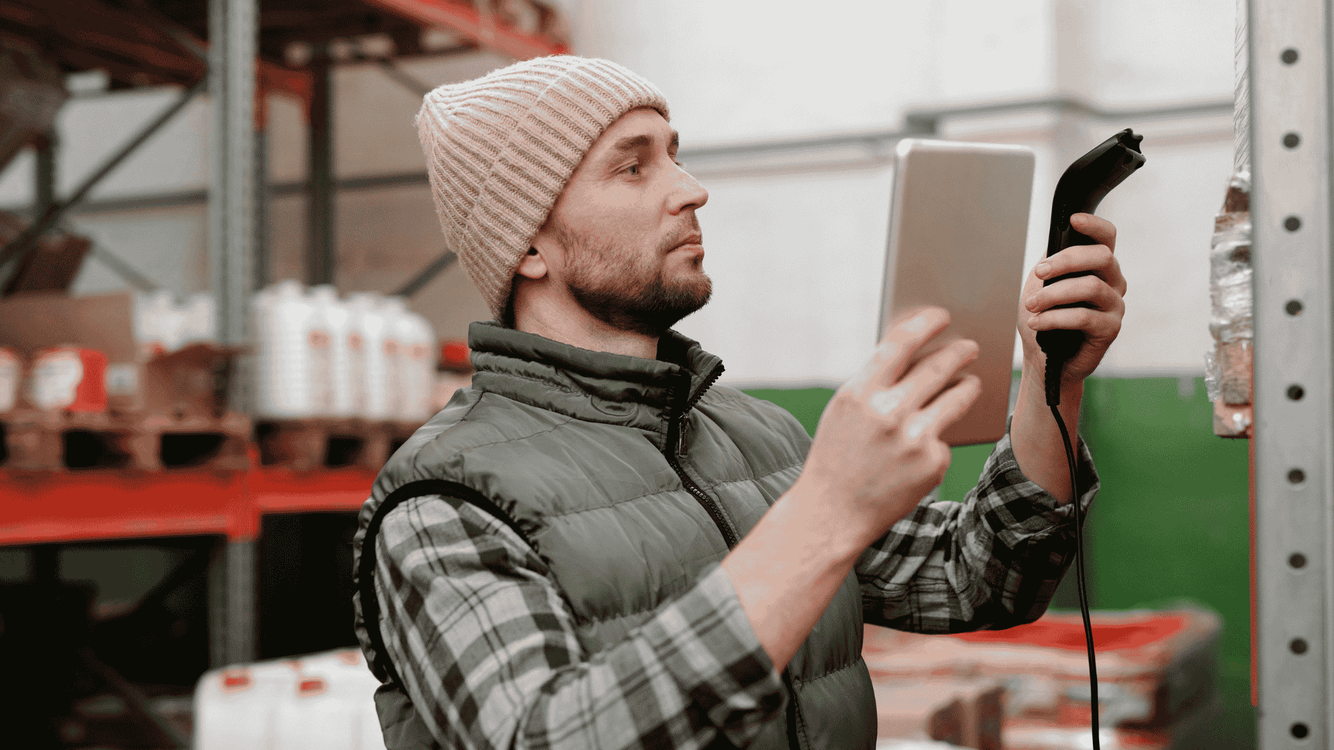 Worker using tablet and scanner in warehouse, demonstrating asset tracking software in use.