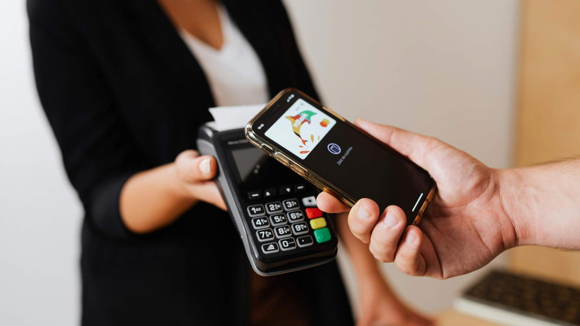 Person using a smartphone to make a contactless payment, demonstrating interoperability between digital wallets and payment terminals