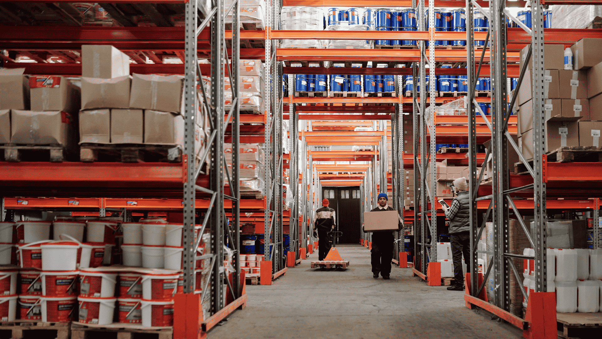 Warehouse workers organizing and transporting boxes between tall shelves stocked with goods and containers