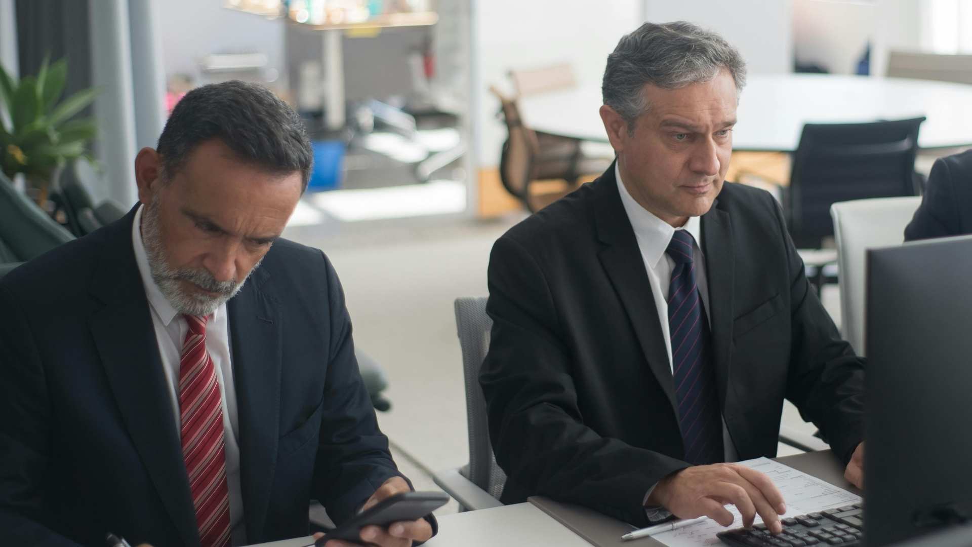 Two financial professionals reviewing data at a computer, representing security in finance through careful monitoring and risk management.